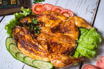 Hot Fried Chicken tobacco with tomatoes and cucumber in a dish close-up. Top view