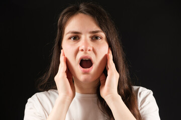A woman with an open mouth holds her cheeks with her hands, exercises for dysfunction of the...