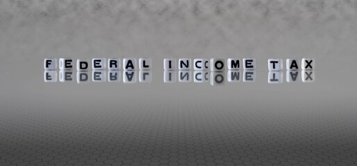 federal income tax word or concept represented by black and white letter cubes on a grey horizon...