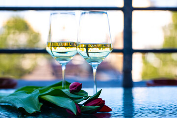 2 wine glasses on glass table with tulips