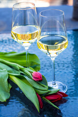 2 wine glasses on glass table with tulips
