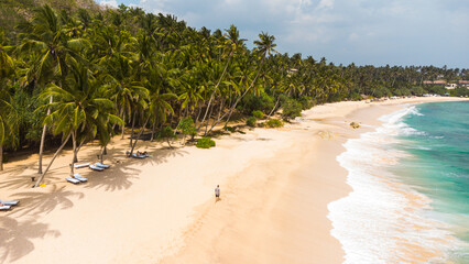 Fototapeta na wymiar Traveler, tourist on a beautiful, paradise tropical beach, ocean and blue water, shot from a drone.