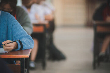 Student taking exam while wearing face mask due to coronavirus emergency. Young woman sitting in...