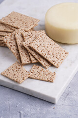 Healthy crunchy crisp crackers with sesame seeds and round cheese kashkaval on marble board