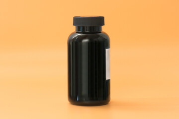 A tall black plastic supplement bottle stands on a yellow background. Workout. Vitamin. Pill. Pack. Prescription. Box. Healthy. Standing. Template