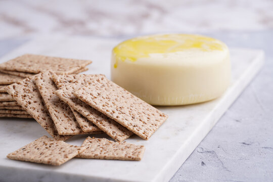 Healthy crunchy crisp crackers with sesame seeds and round cheese kashkaval on marble board