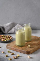 Pistachio milk in bottles on gray background. Lactose free. Vegan nutty plant based milk. Vertical format.