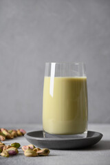 Pistachio milk in glass on gray background. Vegan plant based milk. Vertical.