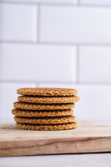 Fototapeta na wymiar Stroopwafel - traditional dutch sirup waffles with caramel filling - stacked on top of each other on a wooden board, white kitchen