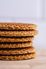 Stroopwafel - traditional dutch sirup waffles with caramel filling - stacked on top of each other on a wooden board, white kitchen, close up