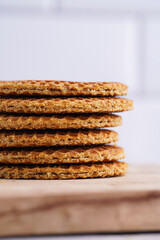 Stroopwafel - traditional dutch sirup waffles with caramel filling - stacked on top of each other on a wooden board, white kitchen, close-up