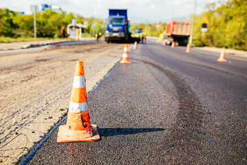 Traffic cones on road. A large layer of fresh hot asphalt. Road construction