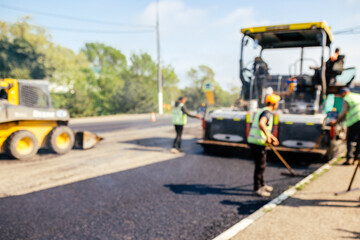Blur background of construction site is laying new asphalt road pavement,road construction workers...