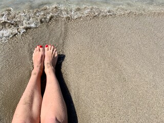 Vacation holidays. Woman feet closeup of girl relaxing on sandy beach enjoying sun on sunny summer day.