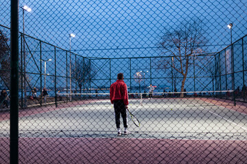 People playing tennis. Photo taken from outside tennis court.