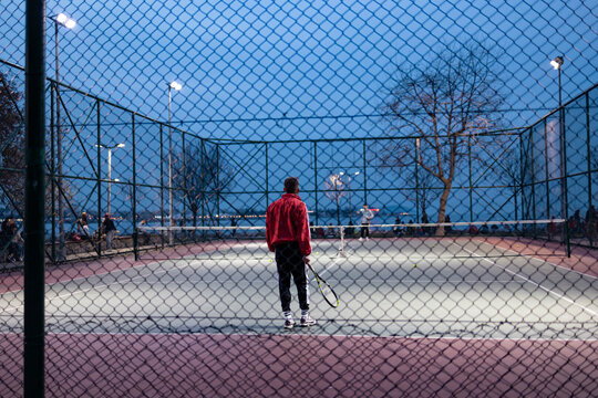 People playing tennis. Photo taken from outside tennis court.