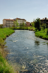 Fototapeta na wymiar Meschio river flows between the houses. Vertical image. Province of Treviso, Italy.
