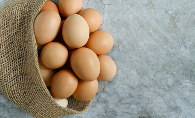 Fresh raw homemade eggs peek out of the burlap on a light gray natural background, close-up, top view, copy space