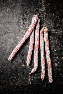 Sticks of salami sausage on the table. On a black background. High quality photo