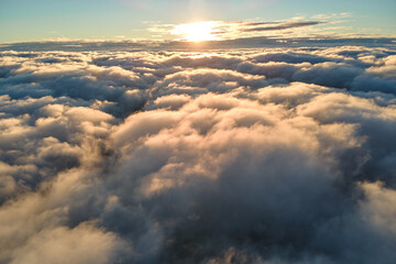 Aerial view from airplane window at high altitude of dense puffy cumulus clouds flying in evening