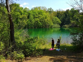 Fototapeta na wymiar 2 girls do yoga exercises by the lake