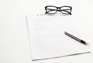 White table with paper contract detail and empty space to sign authorized signature, props with glasses and ink pen, copy space on the left