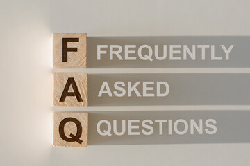 Wooden blocks with word FAQ on light gray baclground. Frequently asked question concept
