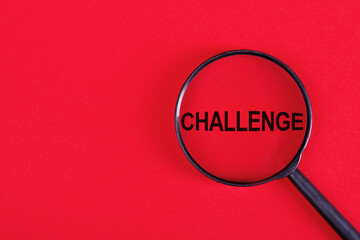 CHALLENGE word written on a magnifying glass on red background.