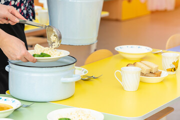 Nannies in the kindergarten are served tables before lunch