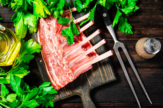 Raw rack of lamb on a parsley cutting board. On a wooden background. High quality photo