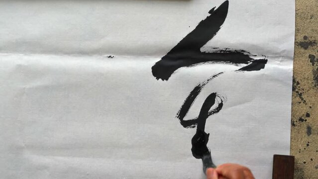 An old calligrapher is creating and writing Chinese calligraphy works. Translation: Chinese Traditional Tang Poems and Calligraphy Poems.