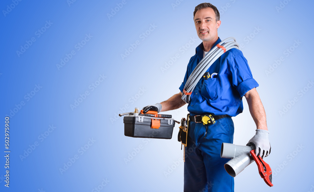 Wall mural Portrait of uniformed plumber with tools and blue isolated background