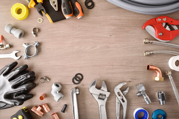 Plumbing materials and tools on wooden workbench top view background