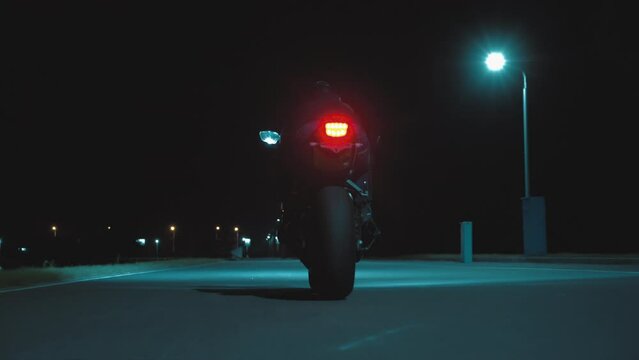 A man rides a sports motorcycle through the city at night