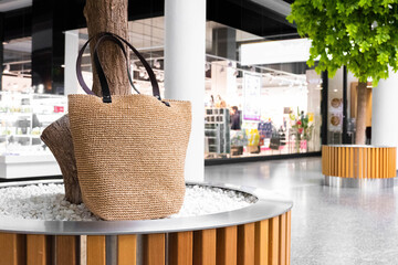 handbag in the mall. No plastic bag and ecology concept, greenfreandly shopping. Handmade bag jute bag in mall lobby near trees.Blank beige tote bag mock up design. - obrazy, fototapety, plakaty