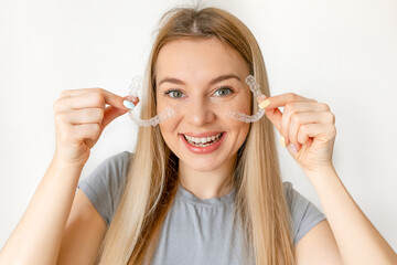 Young smiling woman holding Invisalign braces in studio, dental healthcare and Orthodontic concept
