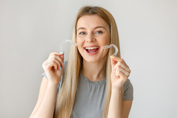 Happy girl with white smile holding transparent removable retainer. Bite correction device.