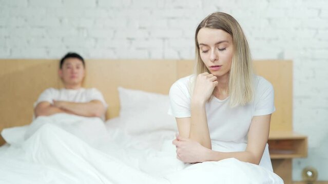 Young unhappy family couple problem in bed. Upset young asian man sitting at home after quarrel. husband and wife are difficult in a relationship. Divorce, marriage, conflict, crisis, love concept