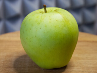 One large apple on a wooden surface, side view. Apple close-up.
