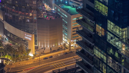 Modern buildings with blue stained glass windows glowing at night in Dubai Media City timelapse, United Arab Emirates