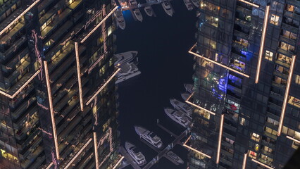 Top view with modern skyscrapers aerial timelapse and water pier of Dubai Marina with night illumination, United Arab Emirates