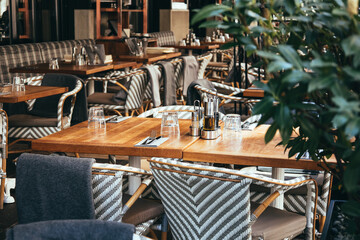 Outdoor empty coffee and restaurant terrace with wooden tables, vintage chairs and warm plaids....