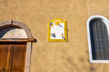 Nice sundial decorated with motifs (bird and sun), on the wall of an old renovated church. Southern Alps, France.