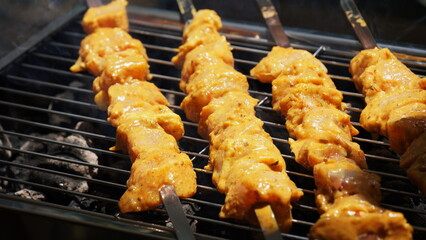 Shashlik - traditional Georgian barbecue. Closeup of raw roasted marinated meat barbecue shish kebab shashlik on steel metal skewers lying grill fire brazier with charcoal.  Making barbecue