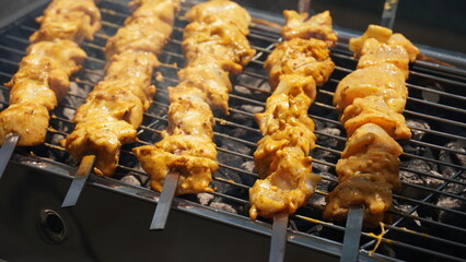 Shashlik - traditional Georgian barbecue. Closeup of raw roasted marinated meat barbecue shish kebab shashlik on steel metal skewers lying grill fire brazier with charcoal.  Making barbecue