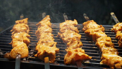 Shashlik - traditional Georgian barbecue. Closeup of raw roasted marinated meat barbecue shish kebab shashlik on steel metal skewers lying grill fire brazier with charcoal.  Making barbecue