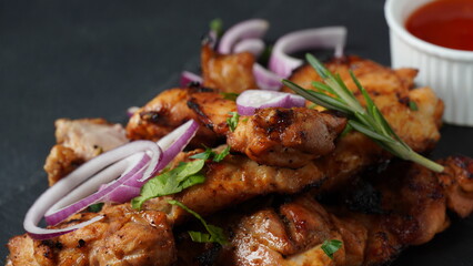 Grilled chicken breast  with sweet onions, herbs, sauce on stone black board. Traditional cuisine. Grill kitchen.