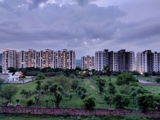 Obraz premium Picture of cityscape with trees and buildings shot against clouds in sky in evening