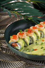 Multicolored sushi and rolls in a gray dish in a restaurant.