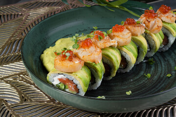 Multicolored sushi and rolls in a gray dish in a restaurant.